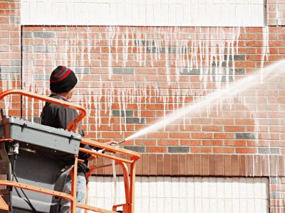 outdoor worker cleaning the exterior wall of building through pressure water